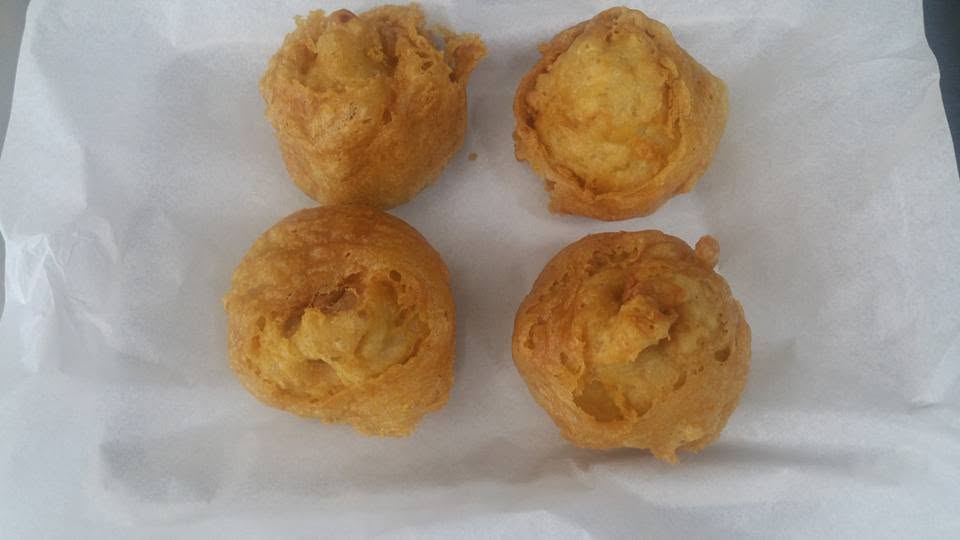 Four golden battered potato scallops on paper